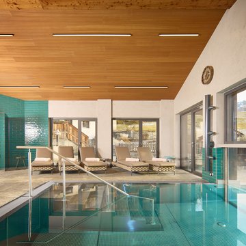 Holiday apartment in Zillertal with panoramic views Indoor pool with lounge chairs and mountain view through large windows